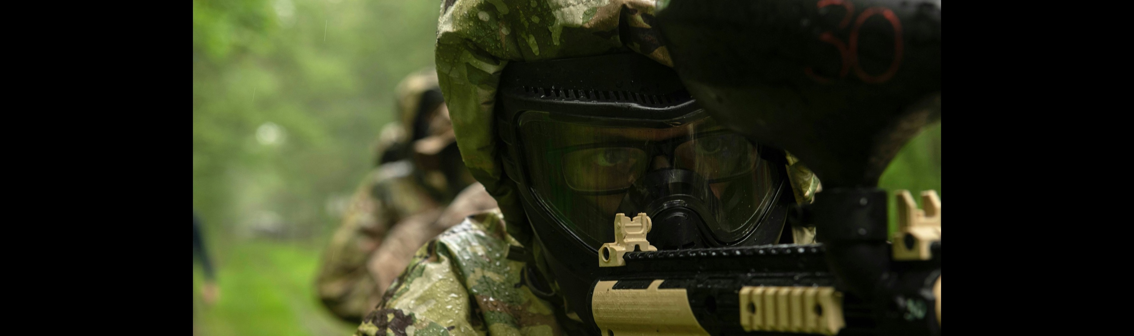 Paintball player aiming in a forest during a team building game