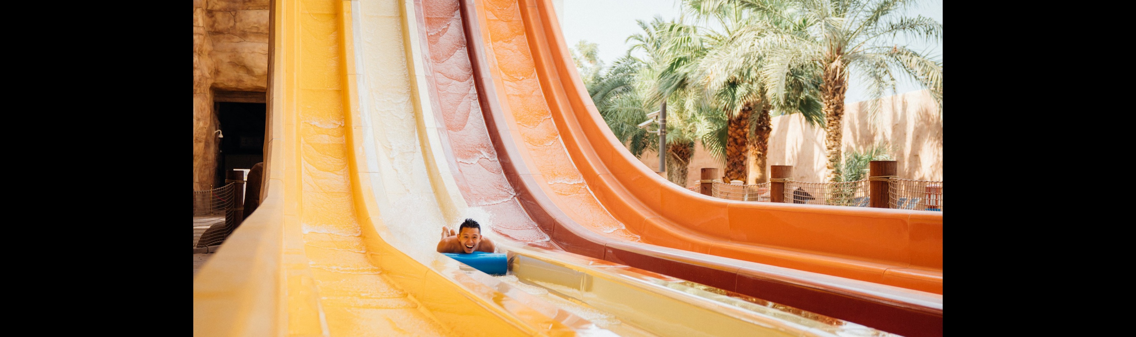Person racing down a multi-lane water slide at an outdoor water park