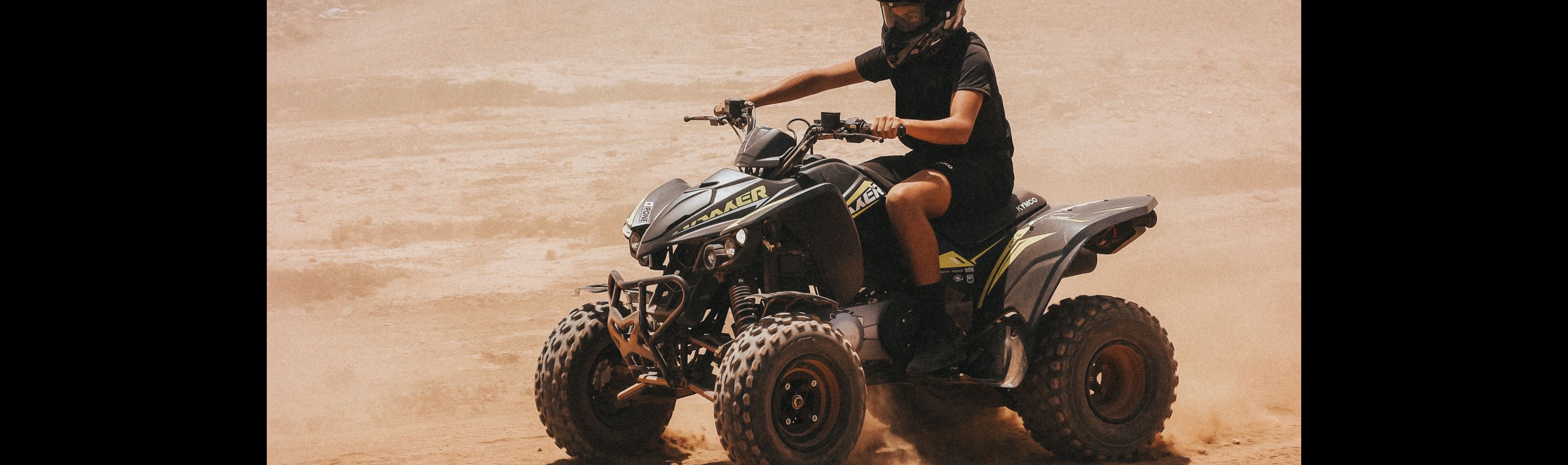 Rider on a quad ATV kicking up dust on a desert trail