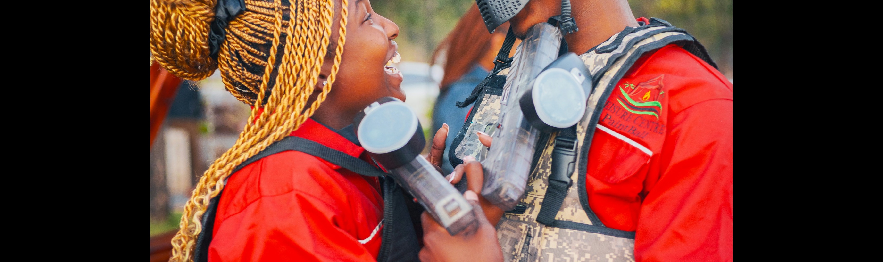 Teammates laughing together in paintball gear after a match
